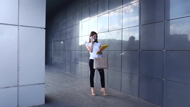 Business Woman Woman Works Near the Business Center Speaks on the Phone Walking With Documents