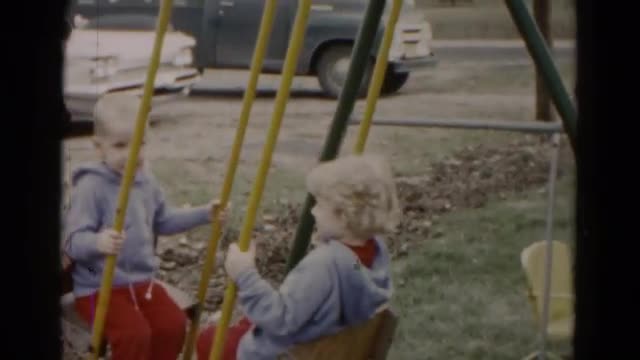 1962: blonde twin siblings playing on seesaw teeter totter playground swing HAGERSTOWN, MARYLAND
