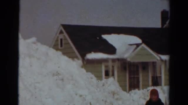 1954: young person stands in front of snow piled high in front of house NEW YORK
