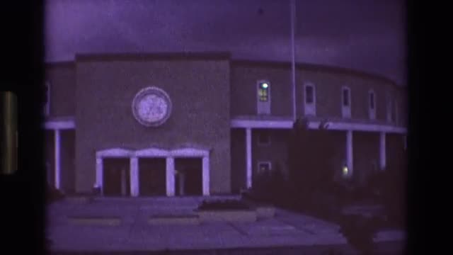 1973: a two-story circular building with a clock on the front, seen at dusk or nighttime NEW MEXICO