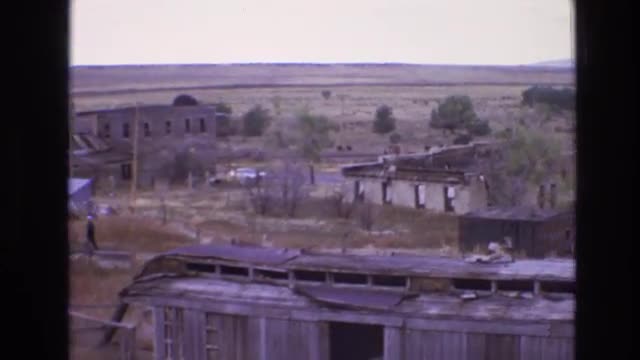 1973: man walks through abandoned rural town with dilapidated buildings and structures NEW MEXICO