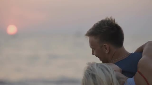 Loving Couple Admiring the Sunset, Kissing and Hugging on the Beach