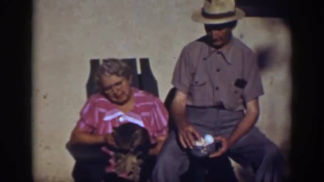1939: lady strokes cat whilst gentleman counts his eggs in a basket AUBURN CALIFORNIA