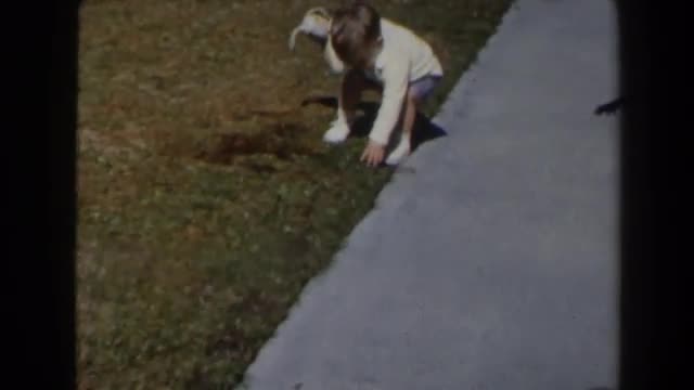 1958: a small boy playing holding a stuffed bunny and playing with a toy car on a sidewalk. LAS VEGA