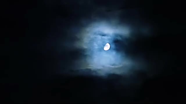 Storm clouds over moon at night on overcast sky