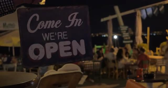 Store sign "closed" is turned to "open" at night on beach cafe background Thessa