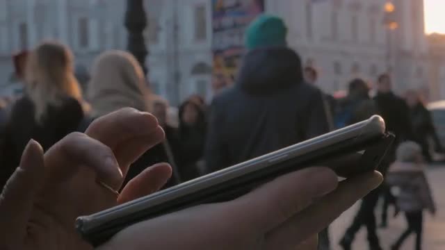 Woman using cellphone in the city at sunset