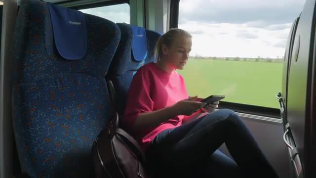 Shot of young blond woman going along train and searching her seat place, modern rail train, Vienna,