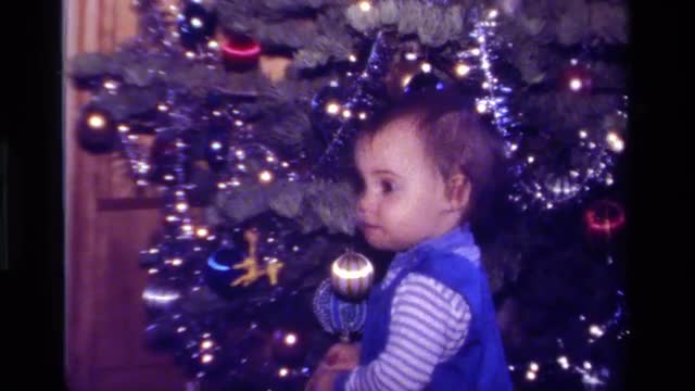 1979: toddler playing with xmas ornaments on tree CALIFORNIA
