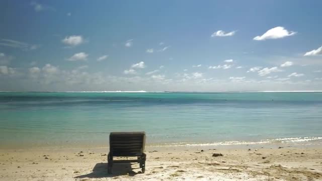 Tropical resort and empty deck-chair by ocean