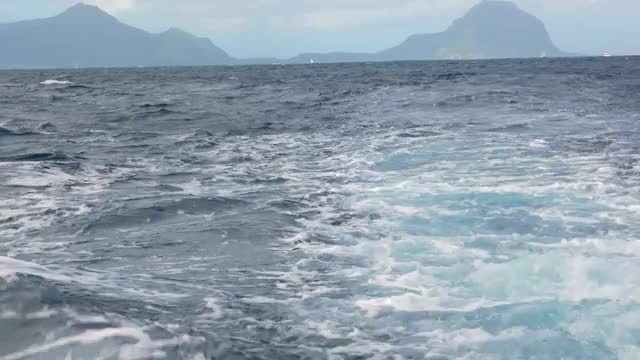 Wavy ocean and distant island, view from the ship