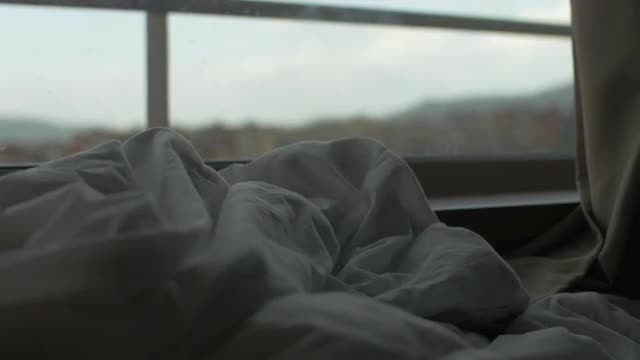 Rumpled blanket on the bed by window