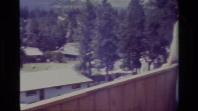 1977: woman leans on terrace fence overlooking low and oblong buildings in wooded area BIG BEAR CALI 1977: woman leans on terrace fence overlooking low and oblong buildings in wooded area BIG BEAR CALI