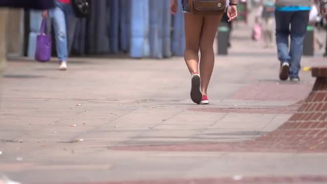 Tan young woman walks down street