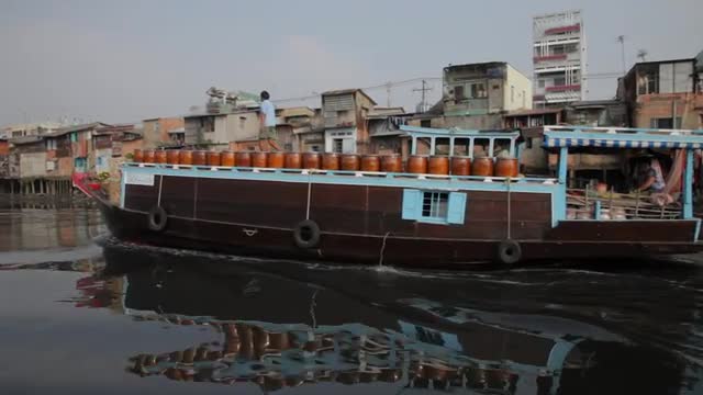 BOAT POV WS PAN Boat Floating Along River with Houses Along Bank / Hoi An, Vietnam