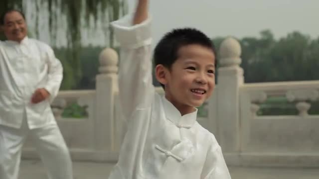 MS SELECTIVE FOCUS Young boy and mature man doing Tai Chi in a park by lake / Beijing, China