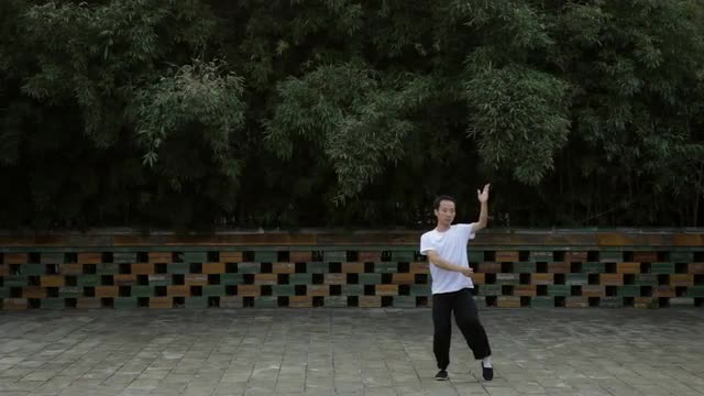 WS Man doing Tai Chi on patio with building in background / Beijing, China