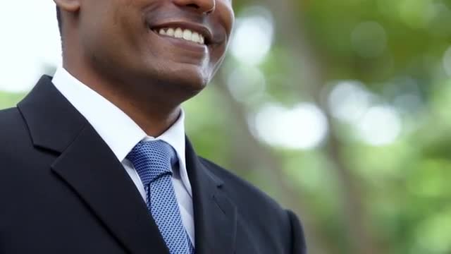 CU LA Mid section of smiling businessman adjusting tie, standing outdoors