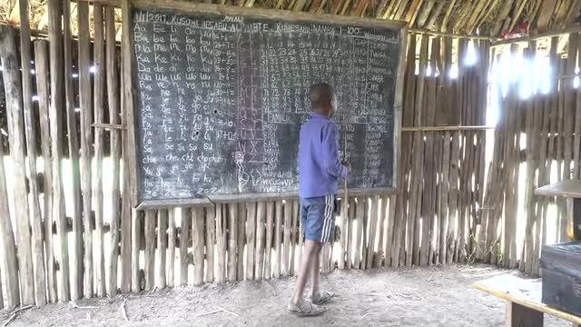 boy at chalkboard in maasai school in Tanzania