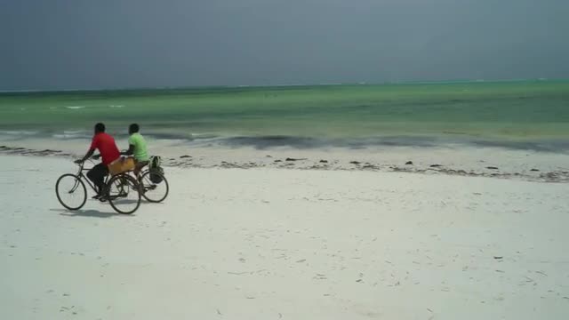 two men cycling on beach on Zanzibar