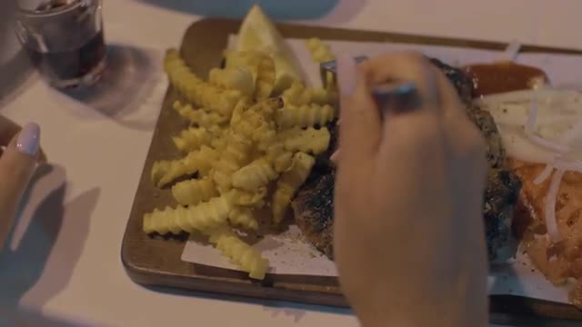 Woman eating meat patties with potatoes and vegetables