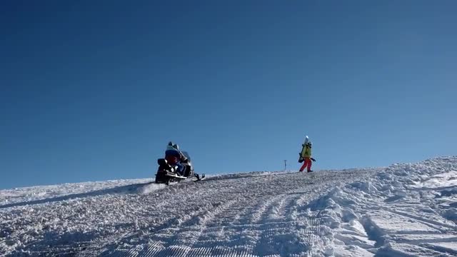 a Snowmobile Rides by With Two Passengers on a Snowed Over Mountain Road in Slow Motion