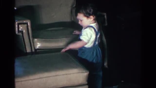 1963: shaky toddler holds himself up against an ottoman and an armchair KENTUCKY