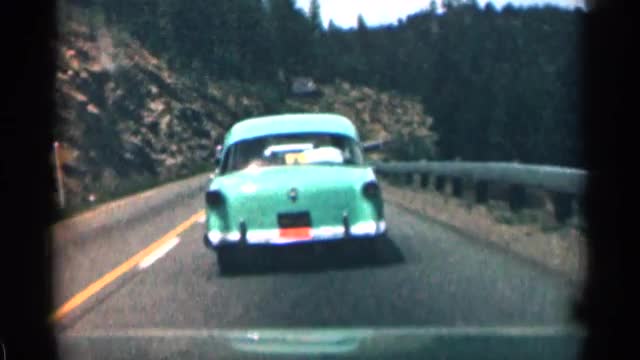 1963: cars driving down a road as a motorcycle passes going in opposite direction. COLORADO