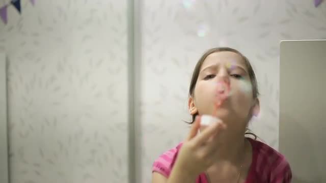 Little girl blows soap bubbles slow motion