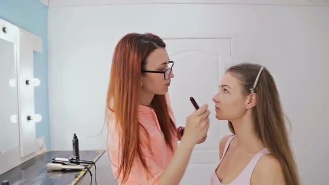 Makeup artist applying liquid tonal foundation on the face of the woman