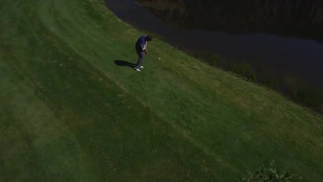 High view shot of golfer hitting chip shot over pond