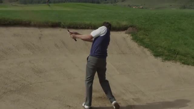 Medium shot of golfer hitting bunker shot onto green