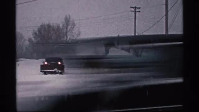 1971: snow area with trees,electric wire is present and a car is moving on the snow area, WISCONSIN