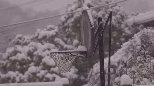 Heavy snow fall with a basketball net in the background