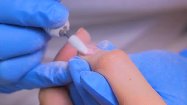 The master uses an electric machine to remove the nail polish