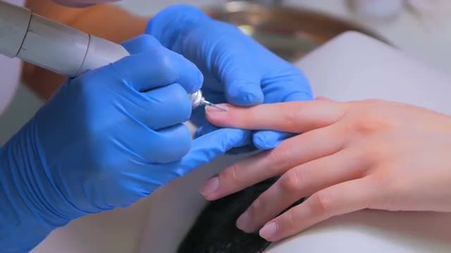 Woman in a nail salon receiving a manicure by a beautician