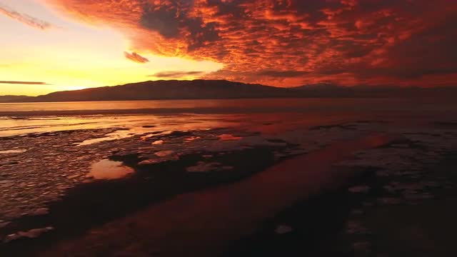 Panning view of icy landscape during bright colorful sunset.