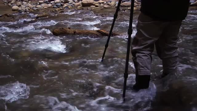 View of photographer standing in river of the Zion Narrows