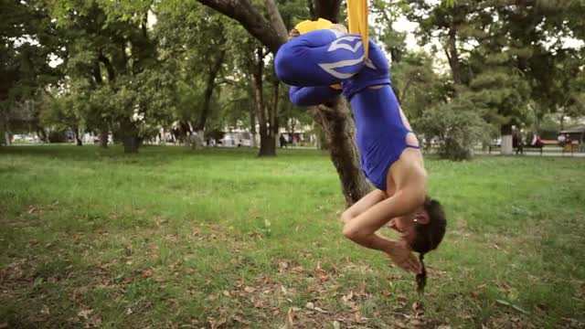 Aerial yoga practitioner stretches herself while suspended on hammock.