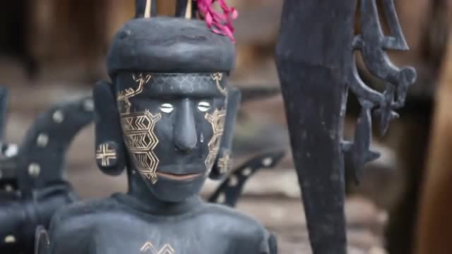Rack focus on face of a female wood carving, medium close