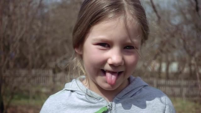 Cute blond little girl puts out her tongue