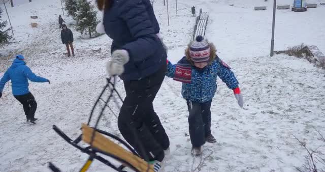 New Year in Bucha Mum Holding Son's Hand Climbing Uphill Going to Sled Again in Park Winter Acti