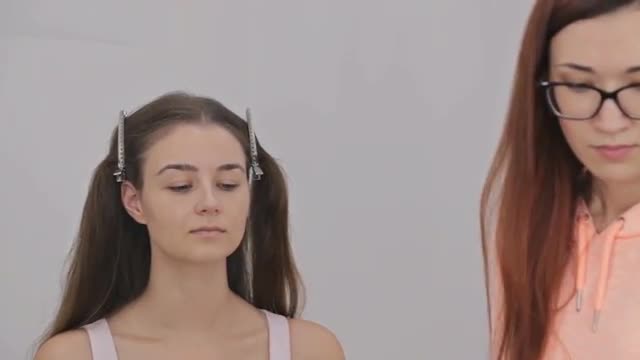 Makeup artist applying liquid tonal foundation on the face of the woman