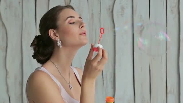 Pretty woman with beautiful make-up and elegant hairstyle blowing bubbles Pretty woman with beautiful make-up and elegant hairstyle blowing bubbles