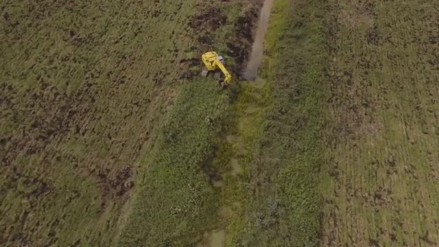 Excavator digging a trench in the field.Aerial video.
