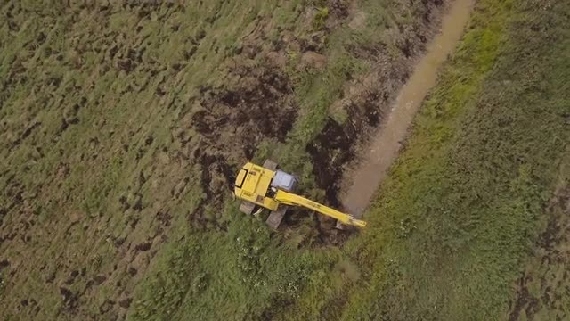 Excavator digging a trench in the field.Aerial video.