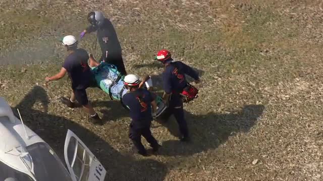 MS POV AERIAL ZO TS Injured man lying on stretcher being loaded into ambulance by ambulance staff / 
