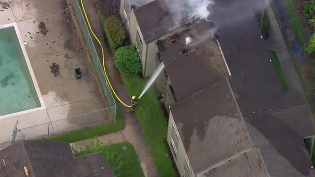 MS POV AERIAL ZI Firefighter hosing water on fire gutted house / United States