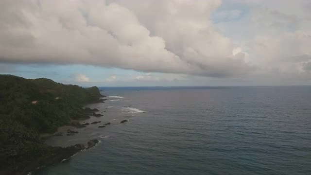 Seascape with tropical island, beach, rocks and waves. Catanduanes, Philippines.