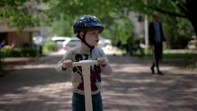 Young Caucasian Boy in Helmet Driving Gyroscooter Through Alley.